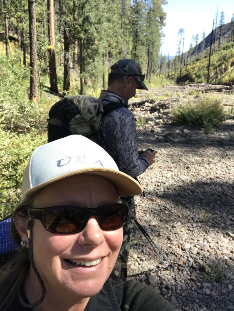 A woman with sunglasses and hat on hiking